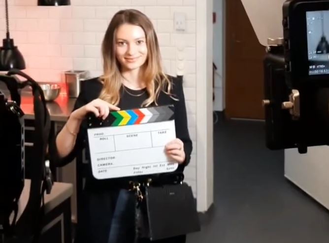 Volontärin Leonie Schwenda mit Filmklappe bei einem Videodreh für Holzmann Medien